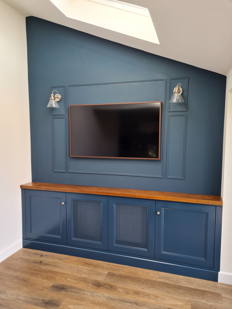 Small living room in Hertfordshire with blue walls, a built-in media wall, brown floor, vaulted and panelled walls.