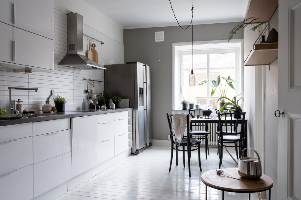 Photo of a large scandinavian single-wall eat-in kitchen in Gothenburg with flat-panel cabinets, white cabinets, concrete benchtops, white splashback, painted wood floors, no island and white floor.