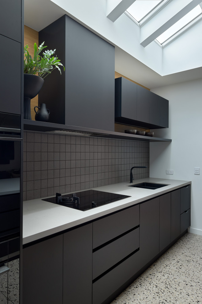 Inspiration för stora moderna grått kök, med släta luckor, svarta skåp, bänkskiva i koppar, grått stänkskydd, stänkskydd i mosaik, svarta vitvaror, betonggolv, en köksö och flerfärgat golv