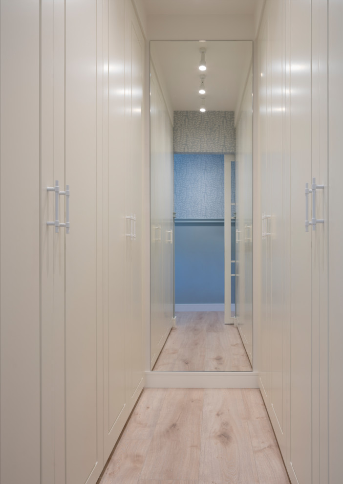Imagen de vestidor unisex clásico renovado de tamaño medio con armarios con paneles con relieve, puertas de armario blancas, suelo laminado y suelo beige