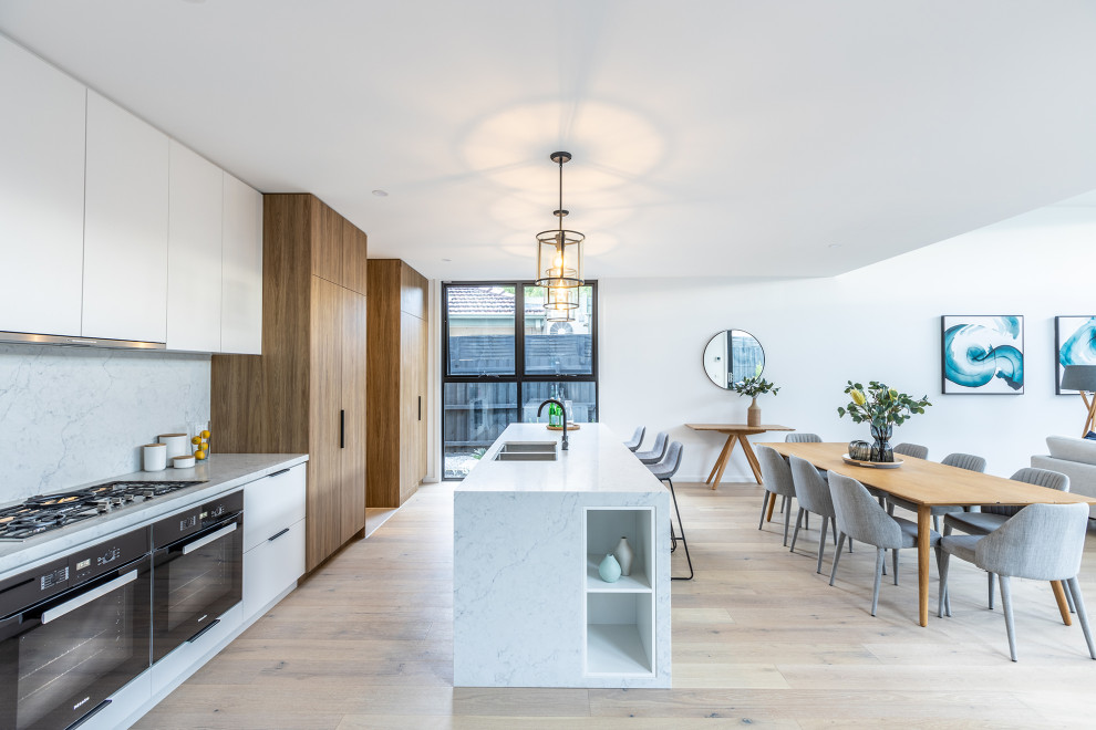 Large contemporary kitchen in Melbourne with an undermount sink, white cabinets, marble benchtops, white splashback, marble splashback, stainless steel appliances, light hardwood floors, with island, beige floor and white benchtop.