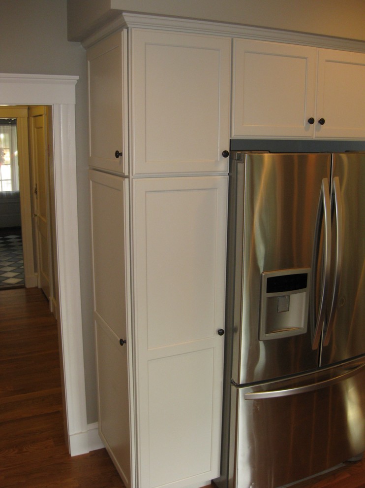 Eat-in kitchen - transitional l-shaped medium tone wood floor eat-in kitchen idea in Boston with an undermount sink, shaker cabinets, white cabinets, granite countertops, white backsplash, ceramic backsplash, stainless steel appliances, an island and black countertops