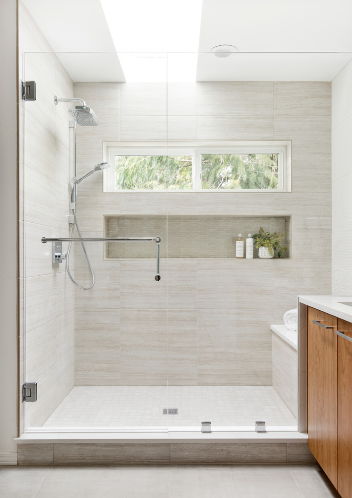 This is an example of a mid-sized contemporary master bathroom in Portland with flat-panel cabinets, medium wood cabinets, an alcove shower, a one-piece toilet, white tile, ceramic tile, grey walls, porcelain floors, an undermount sink, engineered quartz benchtops, beige floor, a hinged shower door and white benchtops.