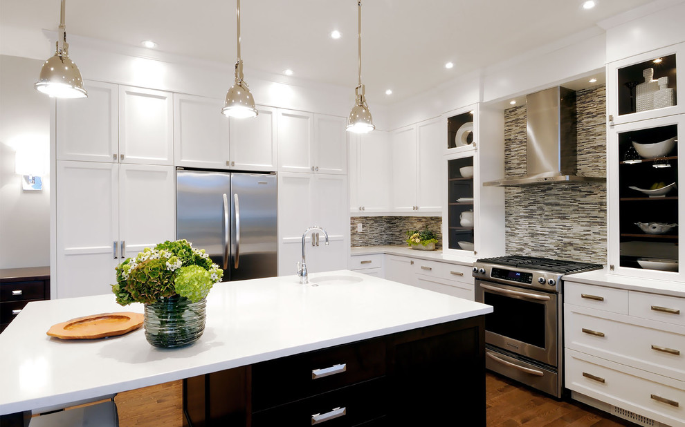 This is an example of a transitional kitchen in Other with glass-front cabinets, stainless steel appliances, white cabinets, multi-coloured splashback and matchstick tile splashback.