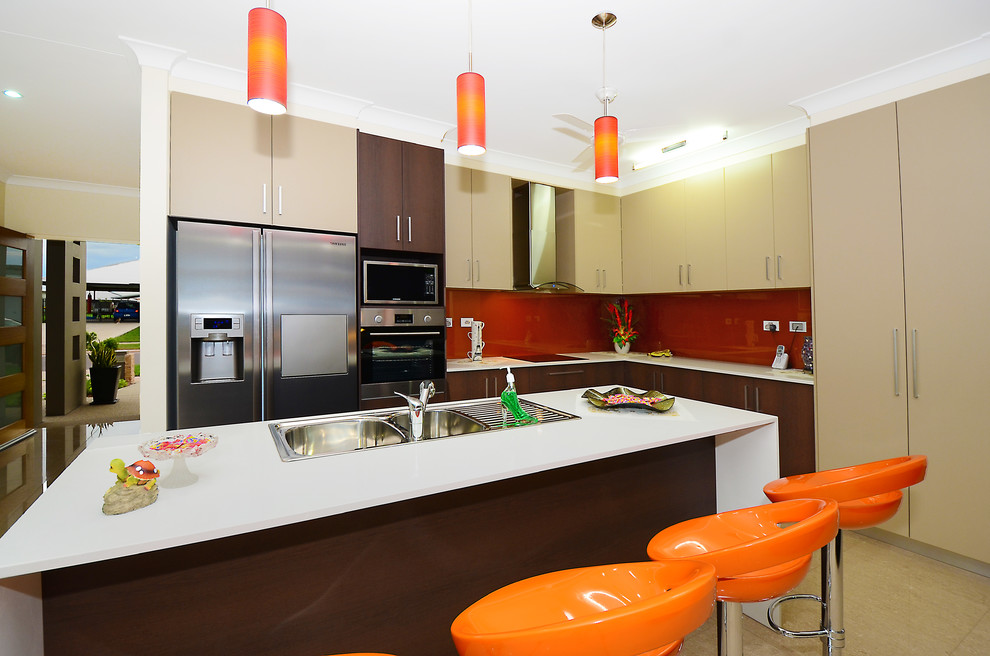 Inspiration for a large contemporary l-shaped eat-in kitchen in Darwin with a drop-in sink, beige cabinets, solid surface benchtops, metallic splashback, glass sheet splashback, stainless steel appliances, porcelain floors and with island.