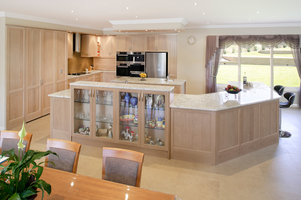Design ideas for an expansive contemporary u-shaped eat-in kitchen in Sydney with an undermount sink, recessed-panel cabinets, light wood cabinets, granite benchtops, brown splashback, glass sheet splashback, stainless steel appliances, travertine floors and multiple islands.