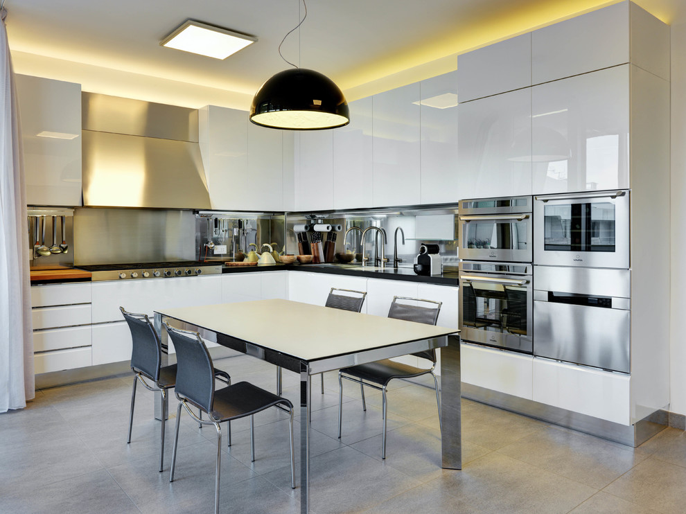 Inspiration for a mid-sized contemporary l-shaped eat-in kitchen in Other with a drop-in sink, flat-panel cabinets, stainless steel cabinets, metallic splashback, metal splashback, stainless steel appliances and grey floor.