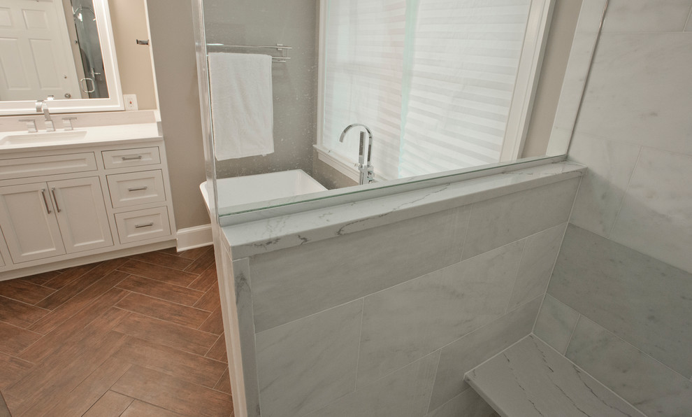 Large transitional master bathroom in DC Metro with beaded inset cabinets, white cabinets, a freestanding tub, a corner shower, beige walls, porcelain floors, an undermount sink, solid surface benchtops, brown floor, a hinged shower door and white benchtops.