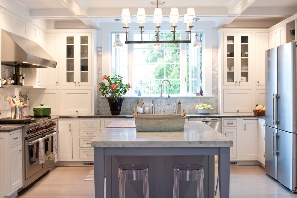 Inspiration for a mid-sized traditional u-shaped separate kitchen in New York with beaded inset cabinets, stainless steel appliances, white cabinets, white splashback, stone tile splashback, marble benchtops, light hardwood floors and with island.