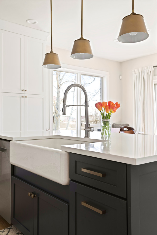 Kitchen - transitional l-shaped light wood floor and brown floor kitchen idea with a farmhouse sink, shaker cabinets, white cabinets, quartz countertops, white backsplash, subway tile backsplash, stainless steel appliances, an island and white countertops