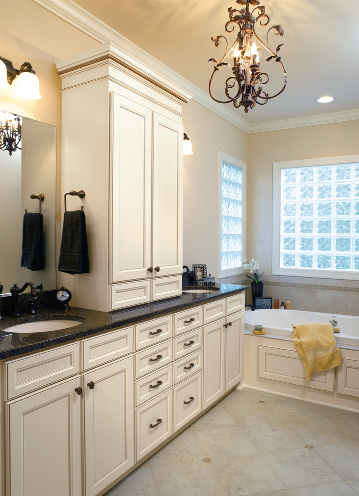 Design ideas for a large traditional master bathroom in Indianapolis with recessed-panel cabinets, white cabinets, a corner tub, a corner shower, ceramic tile, beige walls, ceramic floors, an undermount sink and granite benchtops.