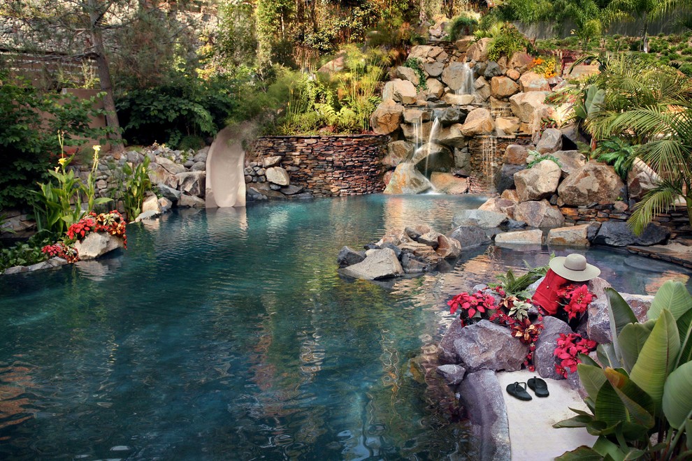 Inspiration for a large tropical backyard custom-shaped natural pool in San Diego with a water slide and natural stone pavers.