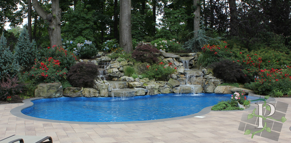 Mid-sized traditional backyard kidney-shaped pool in New York with a water feature and concrete pavers.