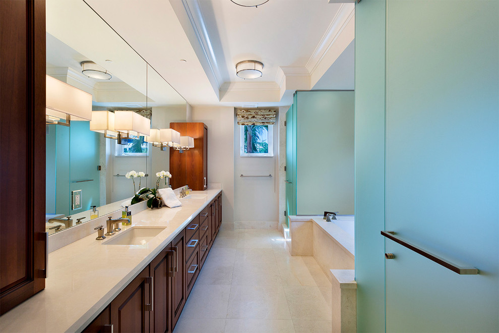 Inspiration for a mid-sized beach style master bathroom in Miami with brown cabinets, an alcove tub, an alcove shower, beige walls, porcelain floors, an undermount sink, marble benchtops, beige floor, a hinged shower door, beige benchtops and recessed-panel cabinets.