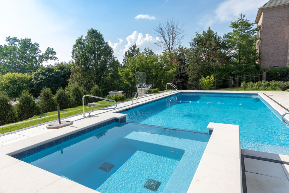 Inspiration for a mid-sized traditional backyard rectangular lap pool in Chicago with a hot tub and natural stone pavers.