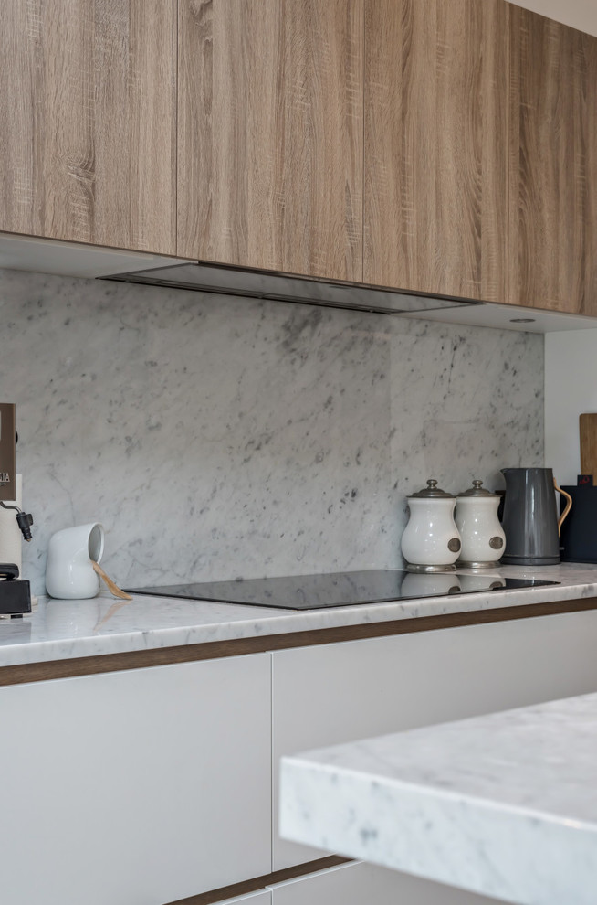 This is an example of a contemporary single-wall eat-in kitchen in London with flat-panel cabinets, grey cabinets, marble benchtops, grey splashback, marble splashback, stainless steel appliances, medium hardwood floors, with island and grey benchtop.