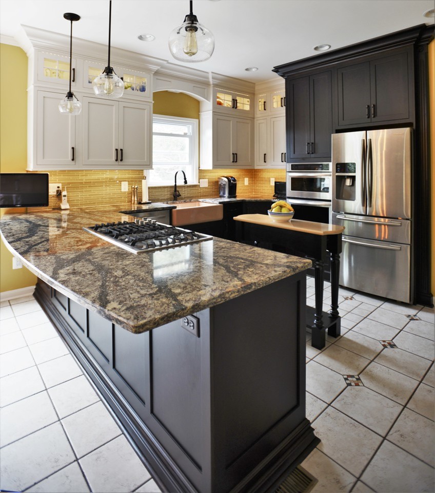 Photo of a large country u-shaped eat-in kitchen in Baltimore with a farmhouse sink, recessed-panel cabinets, brown cabinets, quartz benchtops, yellow splashback, glass tile splashback, stainless steel appliances, ceramic floors and with island.