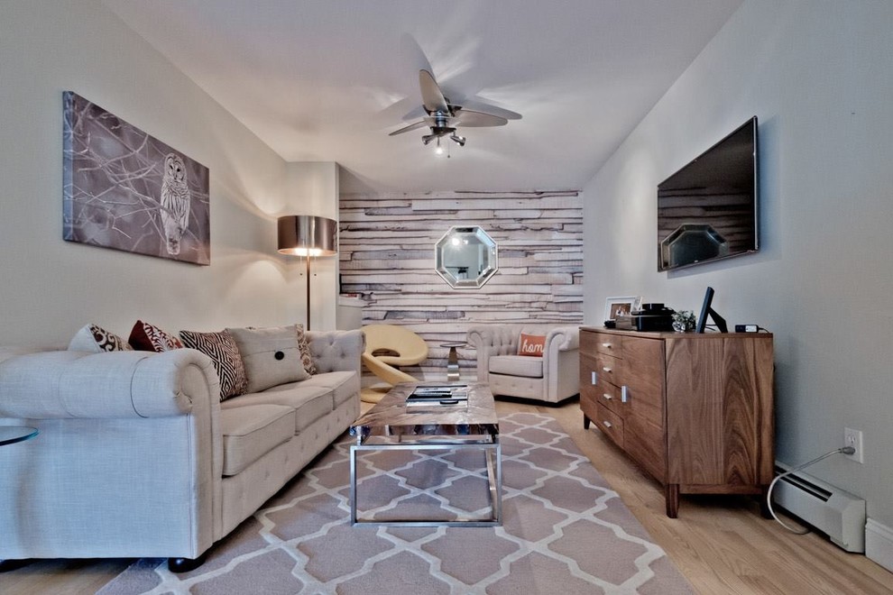 This is an example of a mid-sized transitional enclosed family room in Portland Maine with grey walls, light hardwood floors, no fireplace, a wall-mounted tv and beige floor.