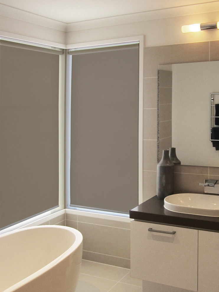 This is an example of a contemporary master bathroom in Melbourne with furniture-like cabinets, beige cabinets, a freestanding tub, beige tile, ceramic tile, grey walls, ceramic floors and a drop-in sink.