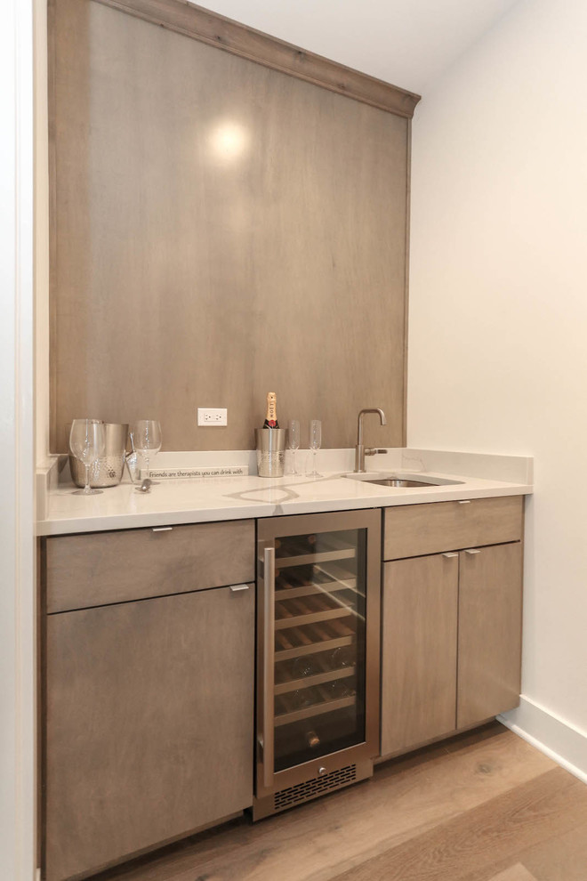 Inspiration for a mid-sized country wet bar in Chicago with an undermount sink, flat-panel cabinets, grey cabinets, quartz benchtops, grey splashback, timber splashback, medium hardwood floors, brown floor and white benchtop.