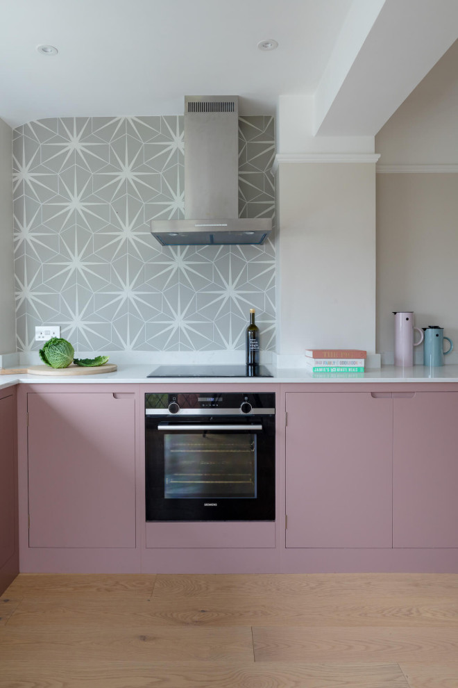 Photo of a mid-sized scandinavian l-shaped eat-in kitchen in Other with flat-panel cabinets, pink cabinets, quartz benchtops, light hardwood floors, no island and white benchtop.