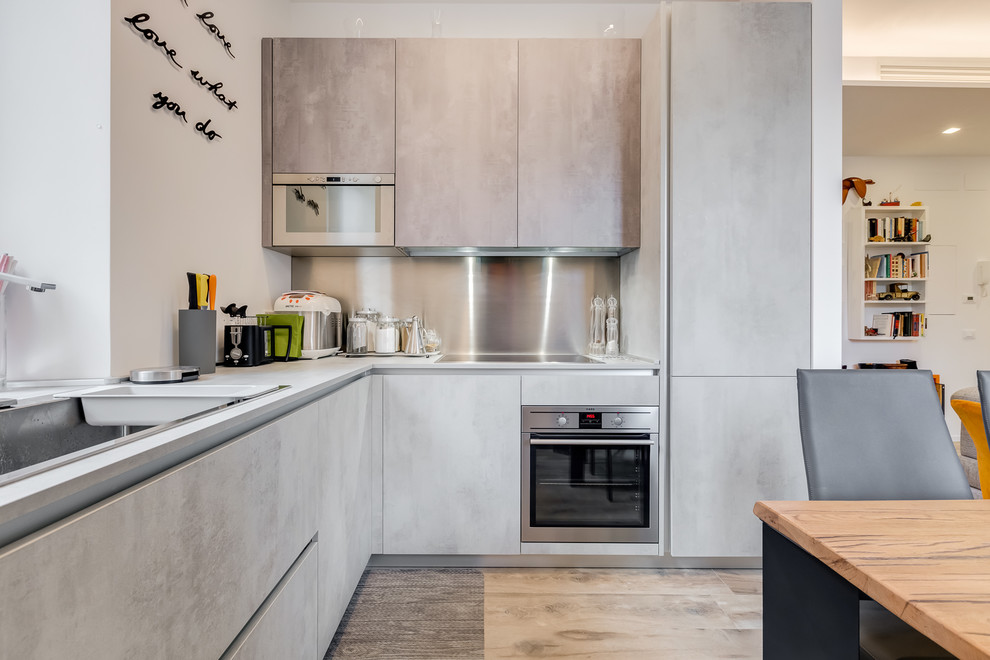 Mid-sized contemporary l-shaped eat-in kitchen in Rome with a single-bowl sink, flat-panel cabinets, metallic splashback, stainless steel appliances, porcelain floors, no island and grey cabinets.