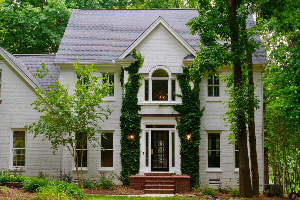 Cette image montre une façade de maison blanche traditionnelle en brique de taille moyenne et à deux étages et plus avec un toit en shingle et un toit noir.