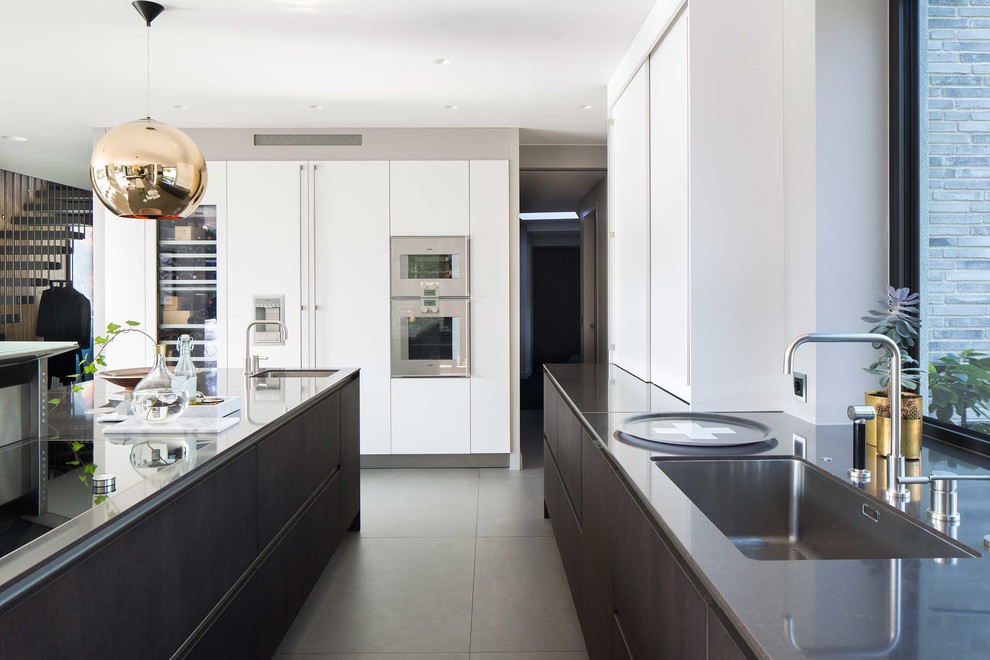 Large contemporary l-shaped kitchen in Malmo with an undermount sink, flat-panel cabinets, white cabinets, panelled appliances, with island, granite benchtops and ceramic floors.