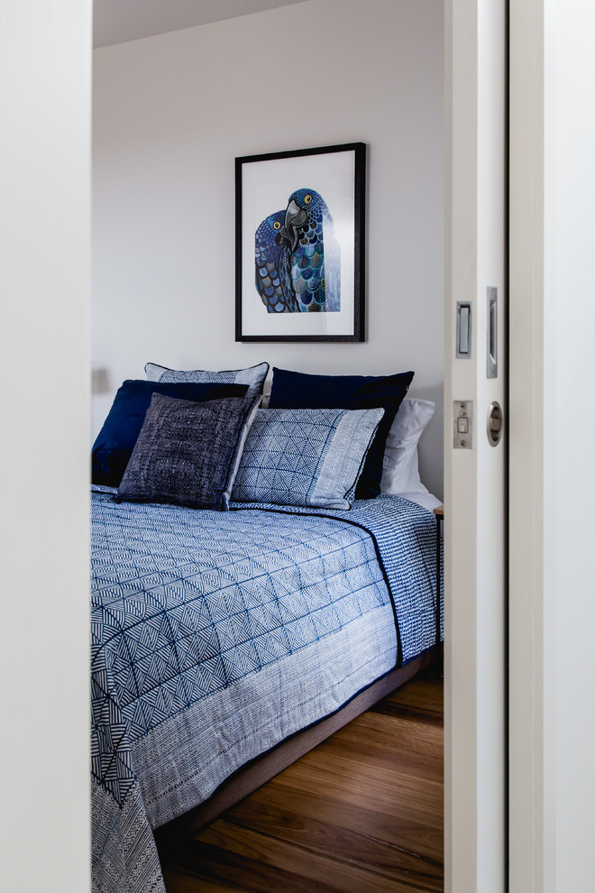 Design ideas for a mid-sized contemporary guest bedroom in Melbourne with white walls and light hardwood floors.