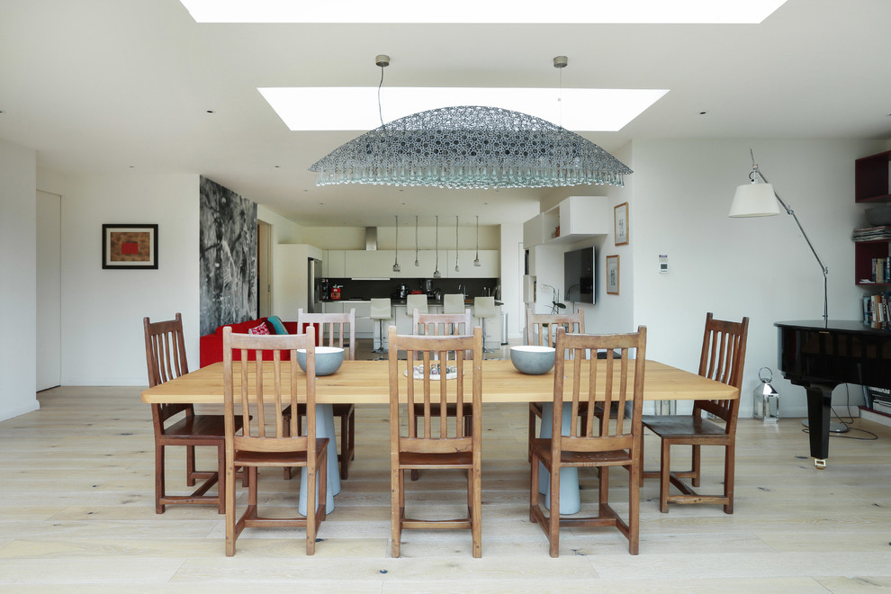 Design ideas for a mid-sized contemporary open plan dining in London with white walls and beige floor.