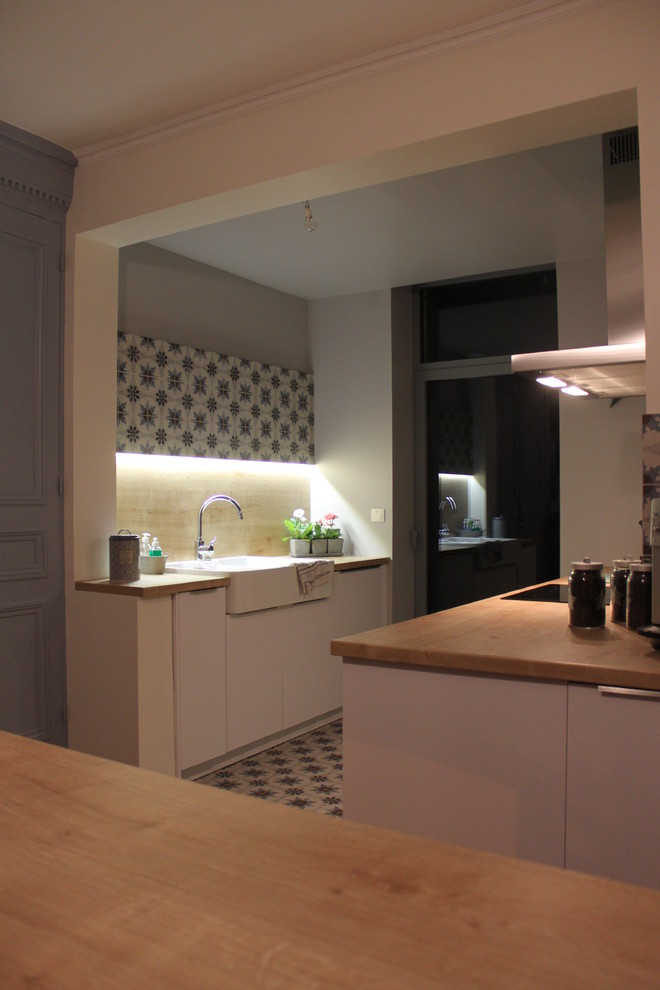 Esempio di una cucina classica di medie dimensioni con lavello integrato, ante a filo, ante bianche, top in legno, paraspruzzi in legno e pavimento in cementine