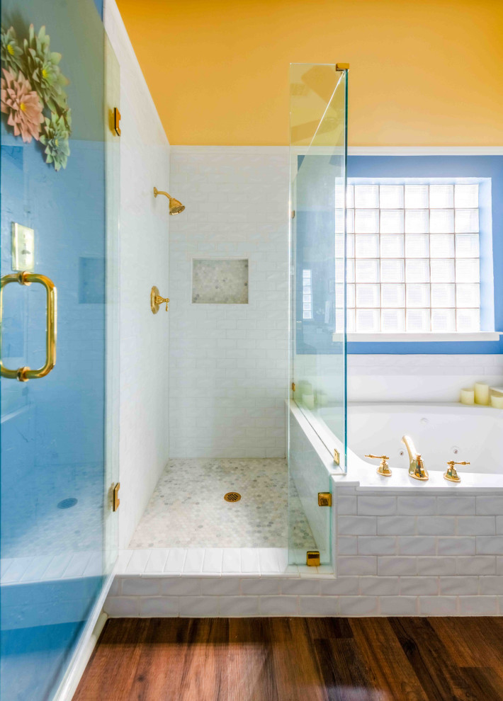 Cette image montre une salle de bain principale traditionnelle de taille moyenne avec un placard avec porte à panneau surélevé, des portes de placard blanches, une baignoire posée, une douche d'angle, WC à poser, un carrelage blanc, un carrelage métro, un mur bleu, un sol en vinyl, un lavabo posé, un plan de toilette en stratifié, un sol marron, une cabine de douche à porte battante, un plan de toilette blanc, une niche, meuble double vasque et meuble-lavabo encastré.