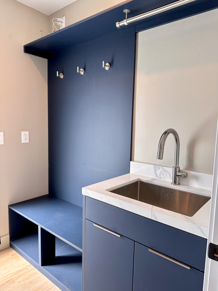 Mid-sized modern galley utility room in Los Angeles with an undermount sink, flat-panel cabinets, blue cabinets, quartz benchtops, vinyl floors, a side-by-side washer and dryer, brown floor and white benchtop.