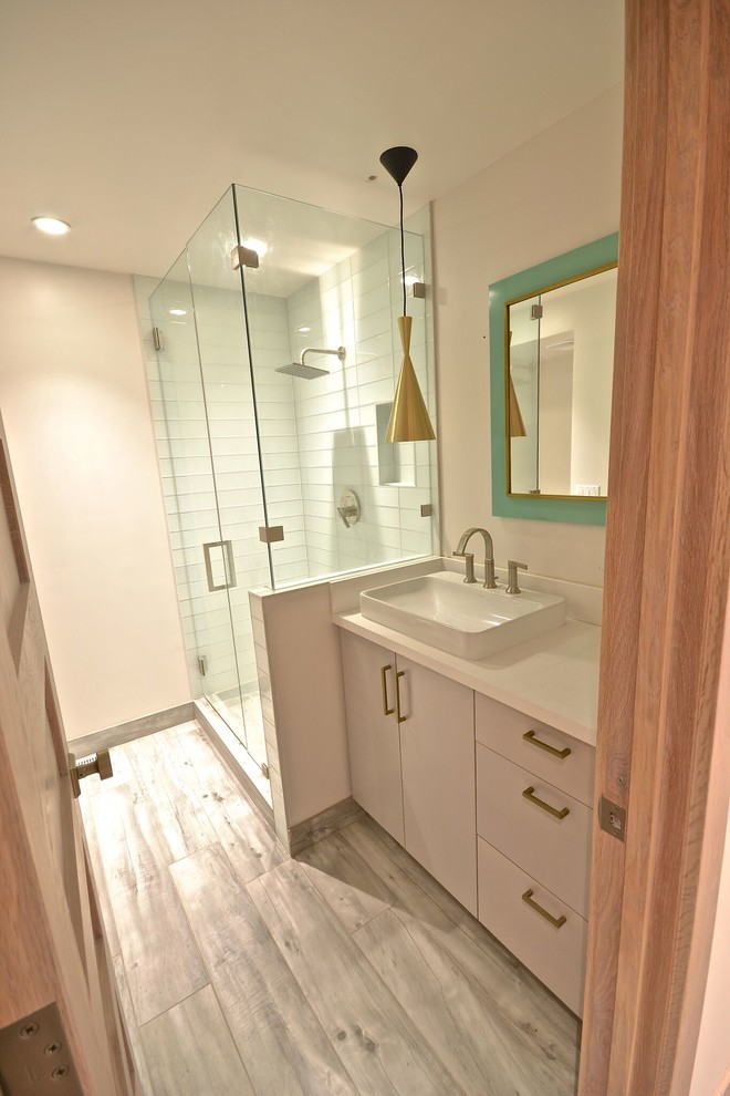 Inspiration for a mid-sized midcentury 3/4 bathroom in Salt Lake City with flat-panel cabinets, white cabinets, a corner shower, white tile, glass tile, beige walls, light hardwood floors, a vessel sink, solid surface benchtops, grey floor, a hinged shower door and white benchtops.