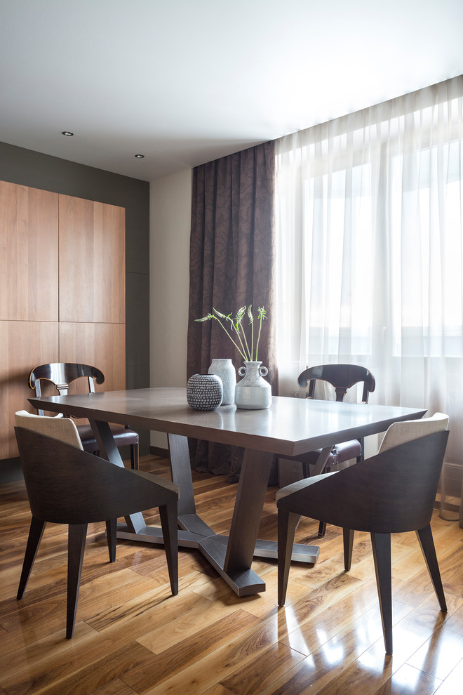 This is an example of a mid-sized contemporary dining room in Moscow with grey walls, medium hardwood floors and brown floor.