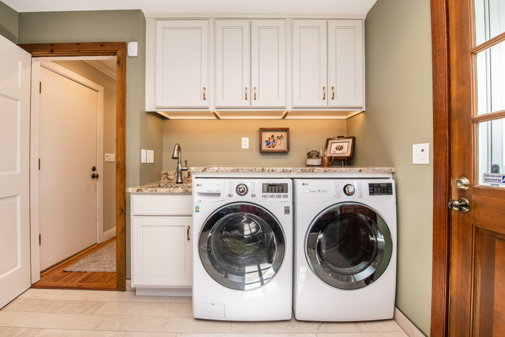 ミルウォーキーにある高級な中くらいなトラディショナルスタイルのおしゃれな家事室 (I型、アンダーカウンターシンク、落し込みパネル扉のキャビネット、白いキャビネット、御影石カウンター、ベージュキッチンパネル、御影石のキッチンパネル、緑の壁、磁器タイルの床、左右配置の洗濯機・乾燥機、ベージュの床、ベージュのキッチンカウンター) の写真