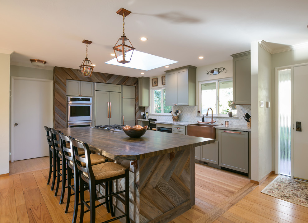 Large transitional l-shaped light wood floor open concept kitchen photo in San Francisco with a farmhouse sink, shaker cabinets, gray cabinets, marble countertops, multicolored backsplash, mosaic tile backsplash, paneled appliances and an island