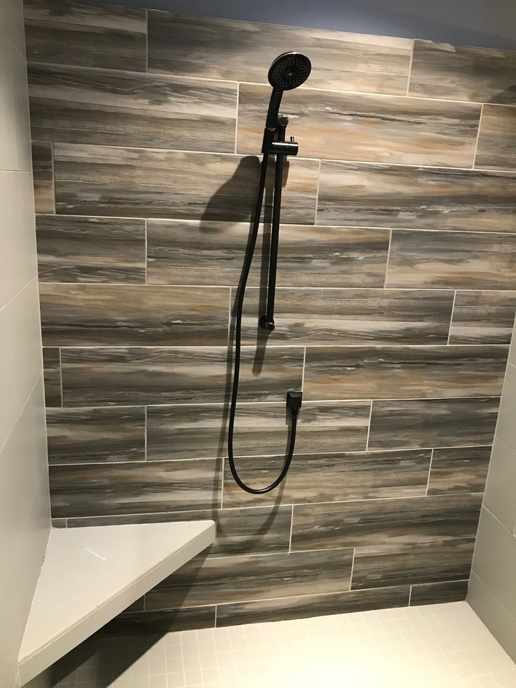 This is an example of a mid-sized transitional master bathroom in Raleigh with shaker cabinets, grey cabinets, an alcove shower, a one-piece toilet, porcelain tile, grey walls, porcelain floors, an undermount sink, onyx benchtops and a sliding shower screen.