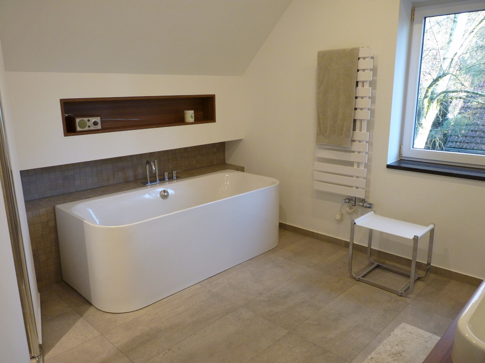 Photo of a large contemporary bathroom in Berlin with a freestanding tub, gray tile, ceramic tile, white walls, flat-panel cabinets, medium wood cabinets and ceramic floors.