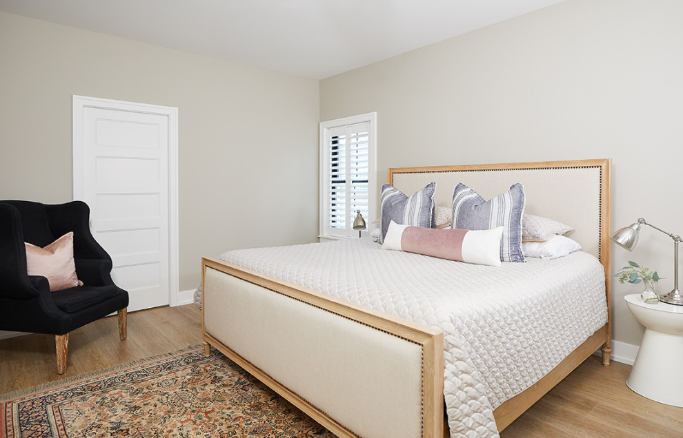 Photo of a beach style bedroom in Grand Rapids with white walls, medium hardwood floors and brown floor.