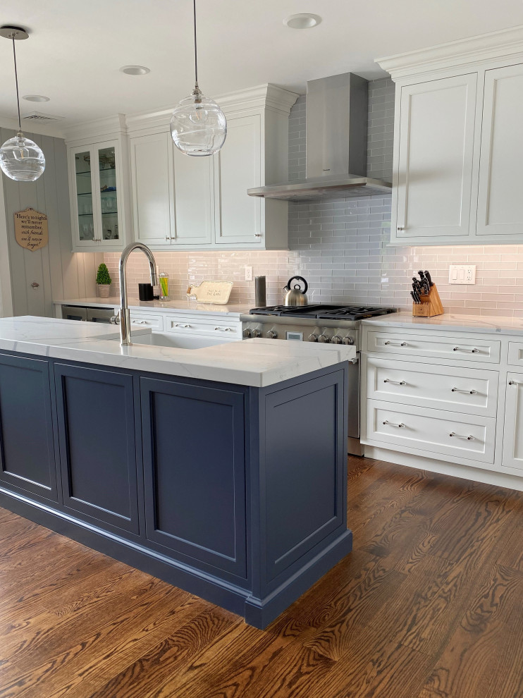 Foto på ett litet vintage vit l-kök, med en undermonterad diskho, luckor med profilerade fronter, blå skåp, bänkskiva i kvarts, grått stänkskydd, stänkskydd i glaskakel, rostfria vitvaror, mellanmörkt trägolv, en köksö och brunt golv