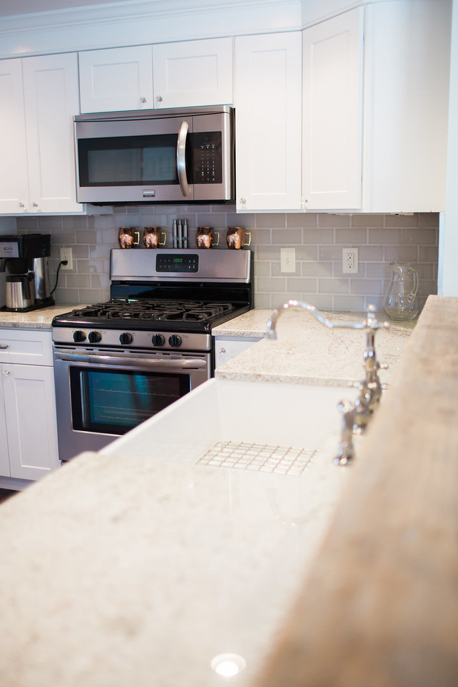 Inspiration for a mid-sized coastal l-shaped dark wood floor eat-in kitchen remodel in Boston with a farmhouse sink, shaker cabinets, white cabinets, granite countertops, gray backsplash, subway tile backsplash, stainless steel appliances and a peninsula