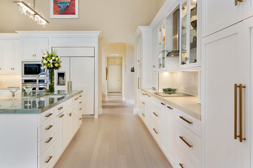 Inspiration for a mid-sized transitional l-shaped light wood floor and beige floor enclosed kitchen remodel in Miami with an undermount sink, recessed-panel cabinets, white cabinets, marble countertops, beige backsplash, mosaic tile backsplash, stainless steel appliances, an island and multicolored countertops