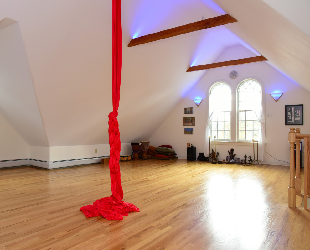This is an example of a large traditional home yoga studio in Boston with white walls and light hardwood floors.