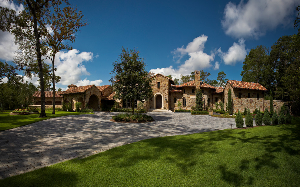 Expansive mediterranean one-storey brown house exterior in Houston with stone veneer.