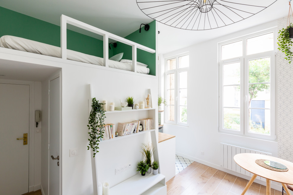 На фото: маленькая открытая гостиная комната в скандинавском стиле с с книжными шкафами и полками, зелеными стенами, ковровым покрытием, черным полом и обоями на стенах для на участке и в саду с