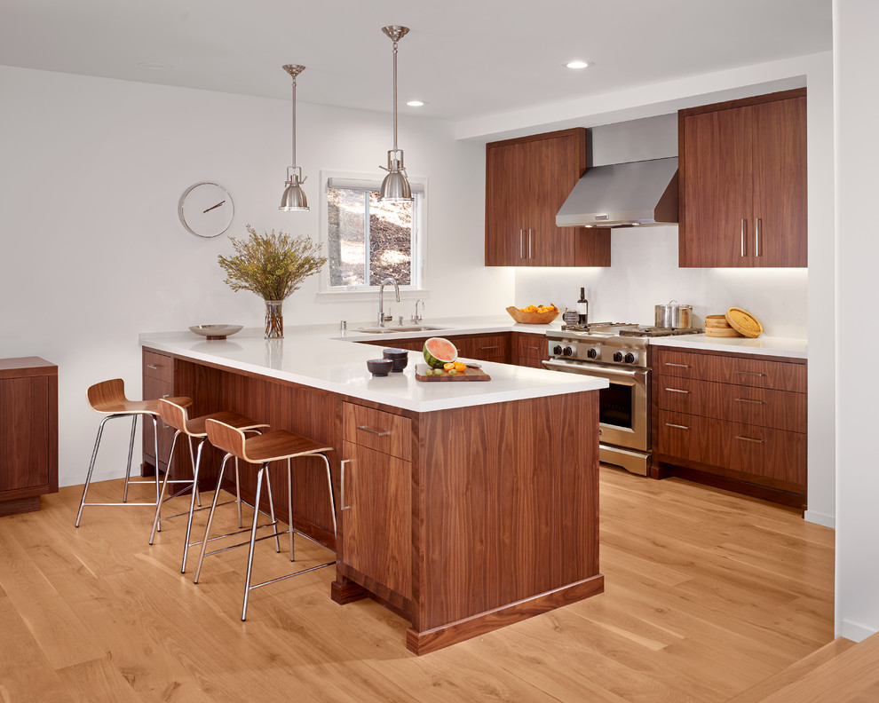 Photo of a small contemporary u-shaped eat-in kitchen in San Francisco with flat-panel cabinets, quartz benchtops, stainless steel appliances, medium hardwood floors, a double-bowl sink, dark wood cabinets, white splashback, stone slab splashback, a peninsula and brown floor.