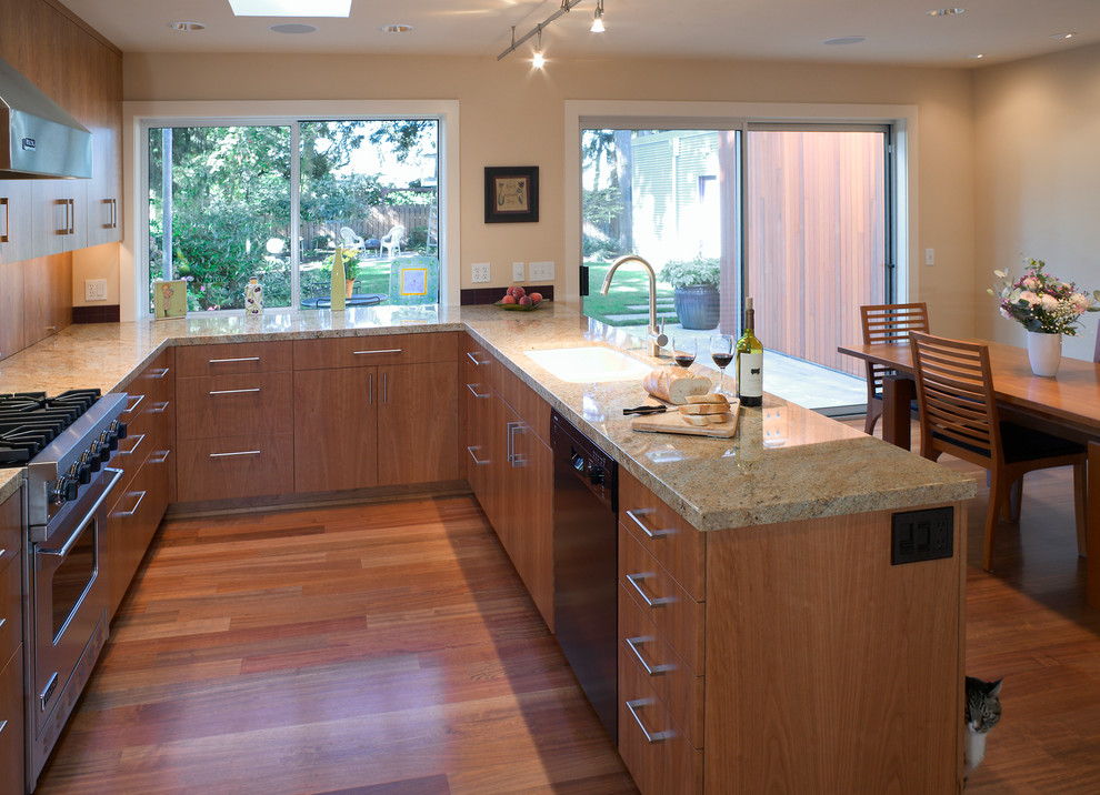 Photo of a contemporary u-shaped eat-in kitchen in Seattle with a double-bowl sink, flat-panel cabinets, granite benchtops, red splashback, ceramic splashback, stainless steel appliances, medium hardwood floors, a peninsula and medium wood cabinets.