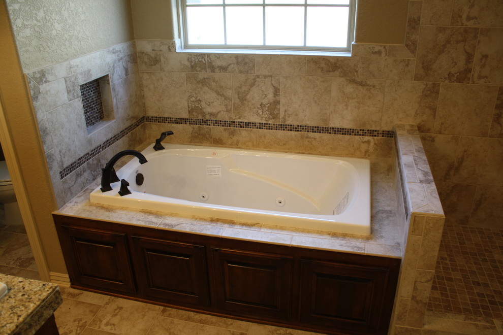 Photo of a large traditional master bathroom in Other with raised-panel cabinets, dark wood cabinets, a drop-in tub, a corner shower, beige tile, stone tile, beige walls and travertine floors.