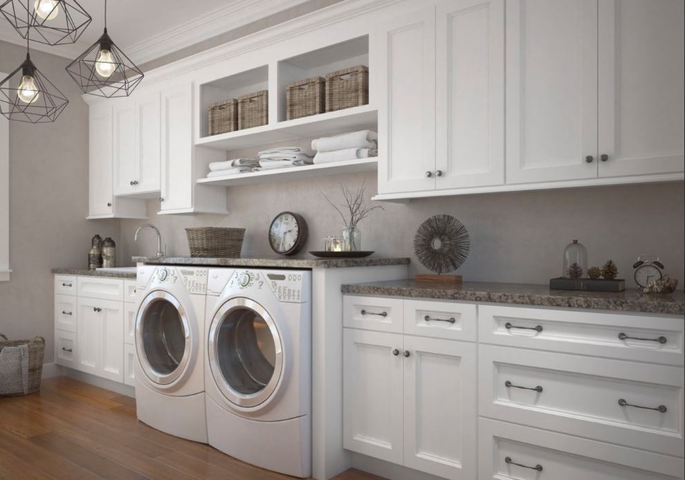 Photo of an expansive transitional single-wall utility room in Philadelphia with a drop-in sink, shaker cabinets, white cabinets, laminate benchtops, grey walls, medium hardwood floors, a side-by-side washer and dryer, brown floor and multi-coloured benchtop.